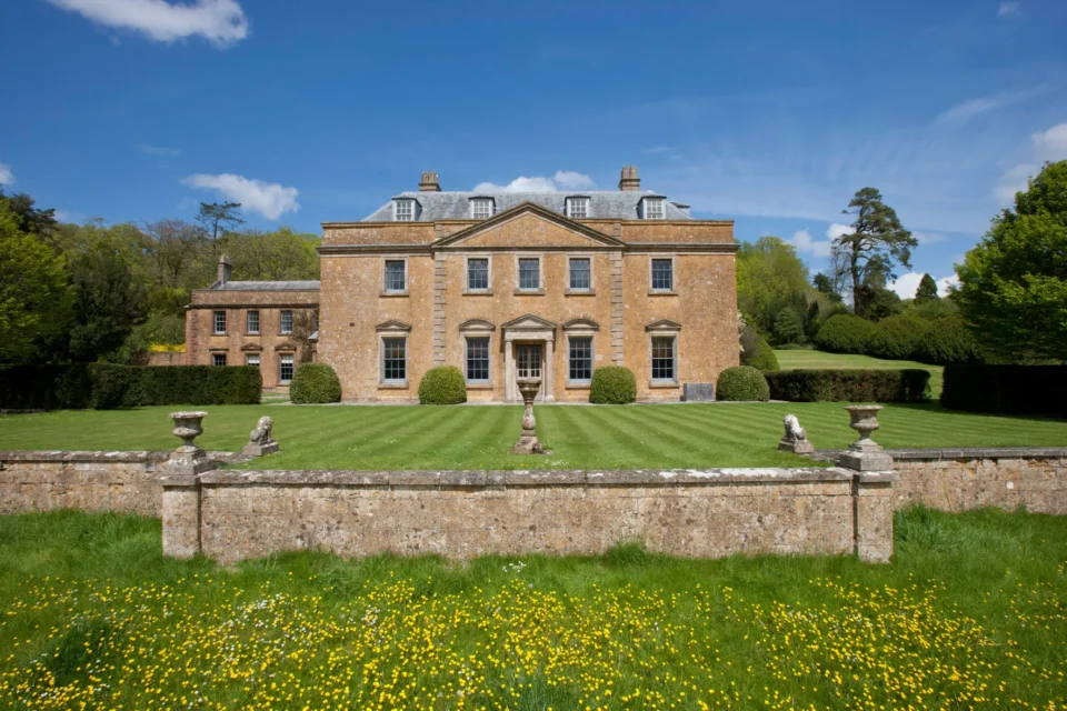 Hotel exterior with manicured lawn and stone wall.