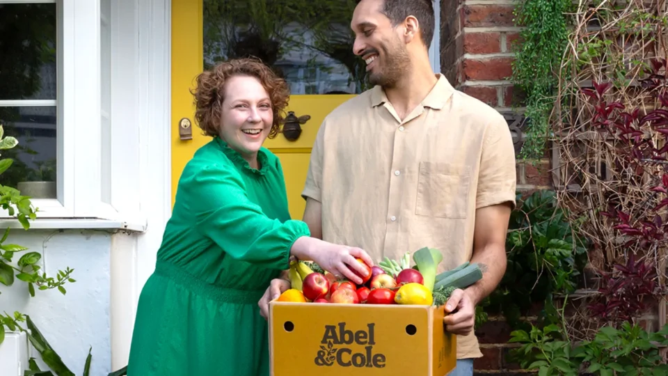 Two people receiving a box of produce from Abel & Cole.